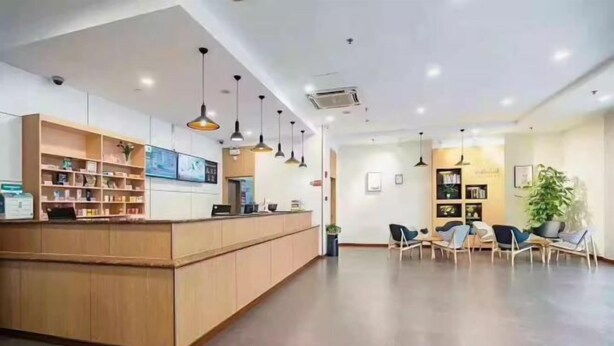 A reception area with a wooden counter, shelves with books and decorative items, and several chairs arranged for waiting. - Kaimanguoji Hotel (Shanghai Dongjing Branch) (Shanghai)