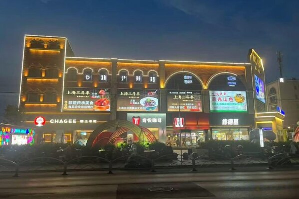 Un edificio de varios pisos con señalización iluminada, incluyendo un llamativo letrero rojo para un restaurante.