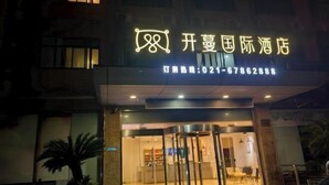 A hotel entrance with a neon sign and a revolving door. - Kaimanguoji Hotel (Shanghai Dongjing Branch) (Shanghai)