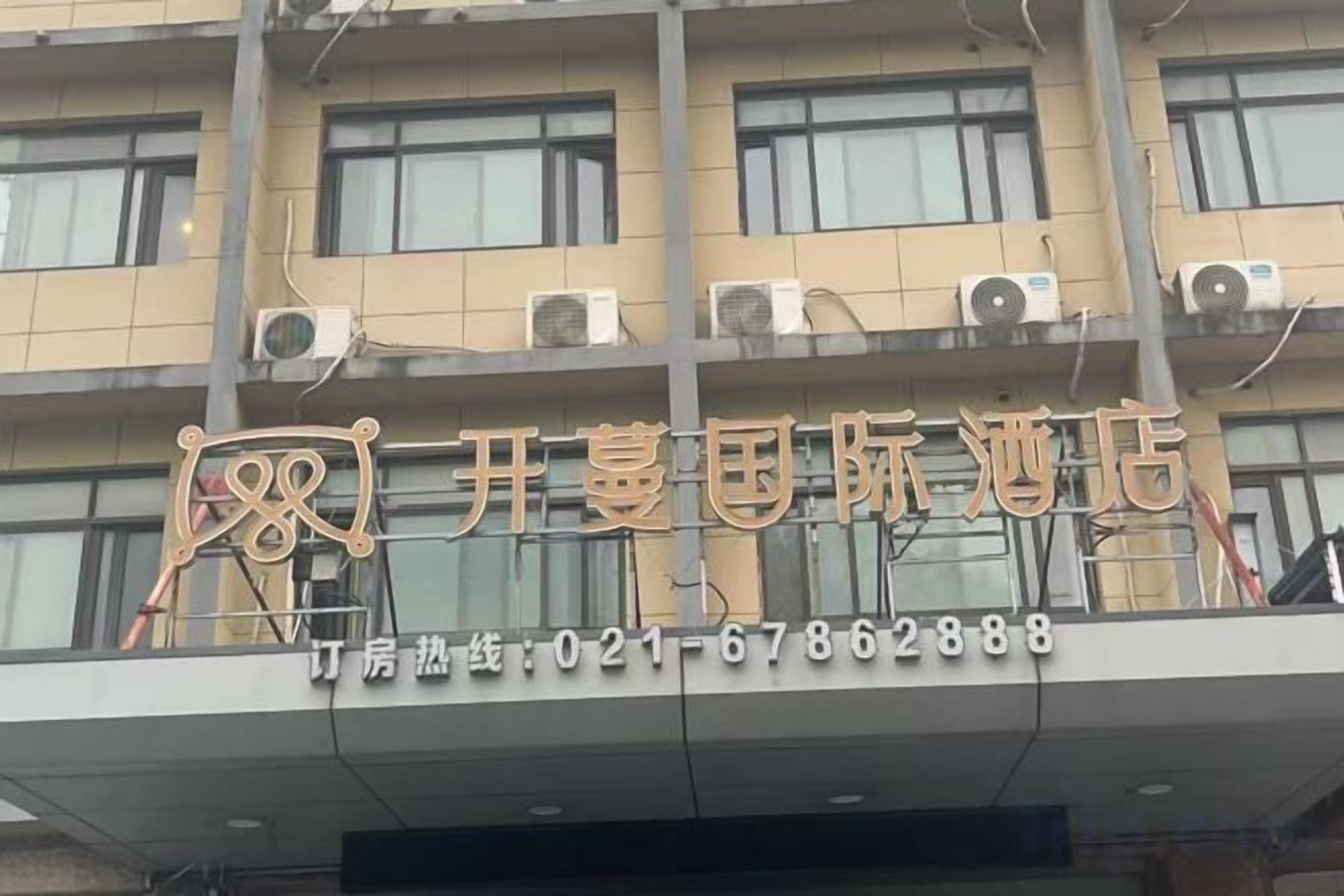 A hotel with a signboard displaying its name and contact number.