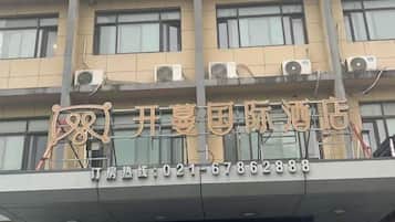 A hotel with a signboard displaying its name and contact number.