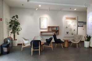 Un espace d’accueil avec des sièges, une plante et des affiches d’information.