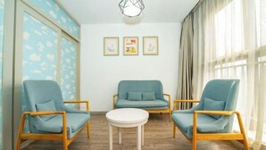 A room with two blue armchairs, a white round table, and a sofa. There are three framed pictures on the wall. - Kaimanguoji Hotel (Shanghai Dongjing Branch) (Shanghai)