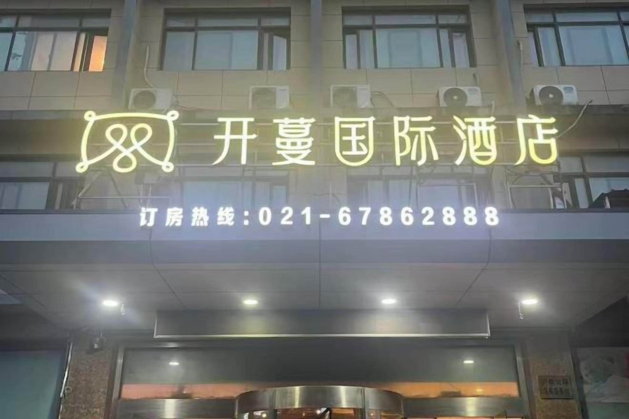 A hotel sign with a neon sign and a contact number.