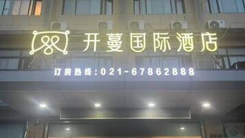 A hotel sign with a neon sign and a contact number.