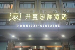 Une enseigne d’hôtel avec un panneau lumineux au néon et un numéro de téléphone.