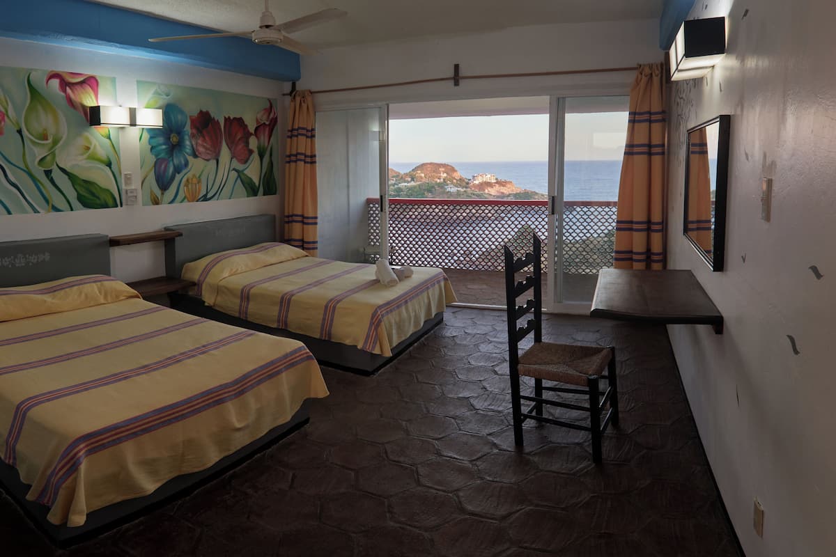 Ein Hotelzimmer mit zwei Betten, einem Sessel, einem Balkon mit Aussicht und einem dekorativen Wandbild.