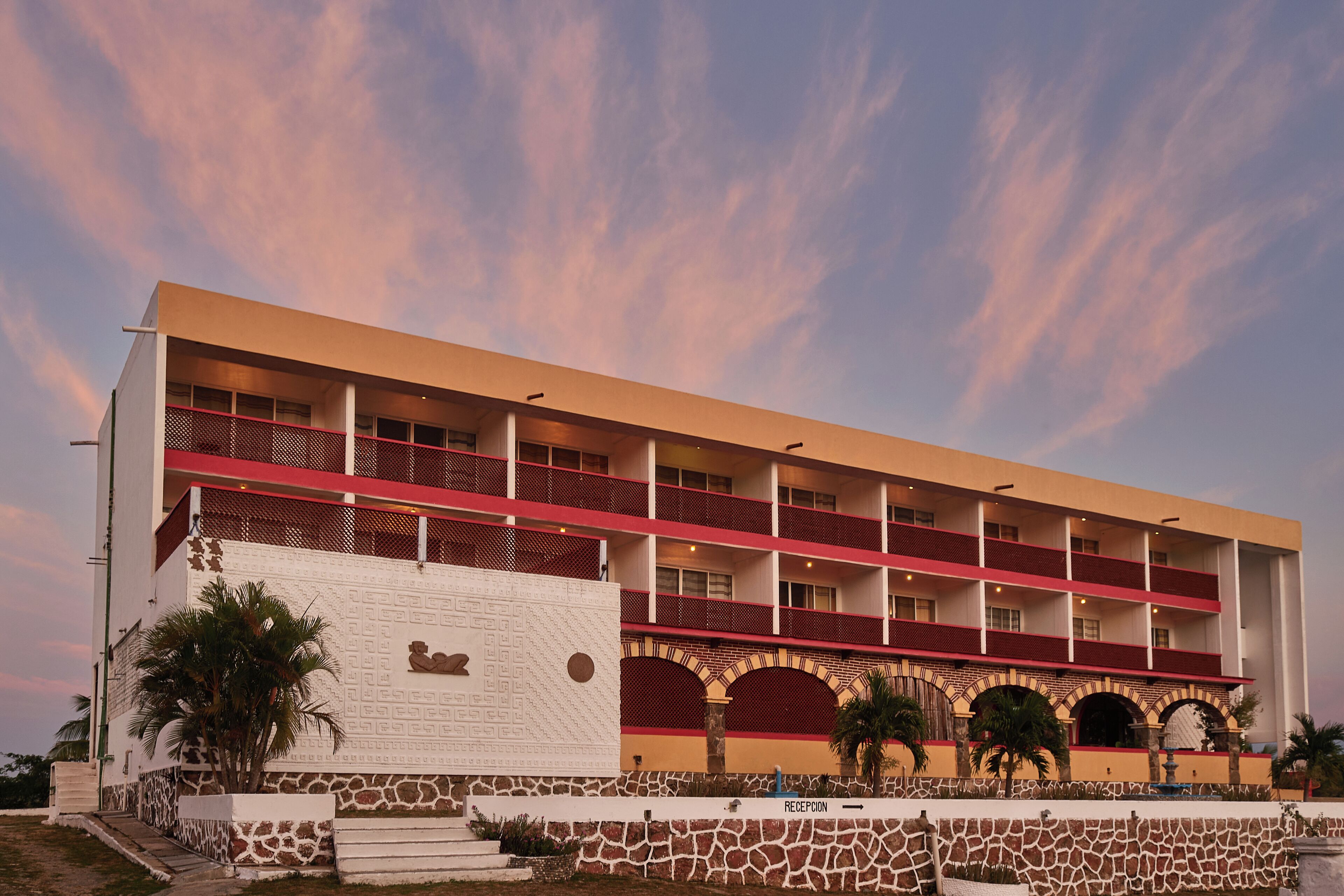 A multi-story hotel with a flat roof, multiple balconies, and a reception area.