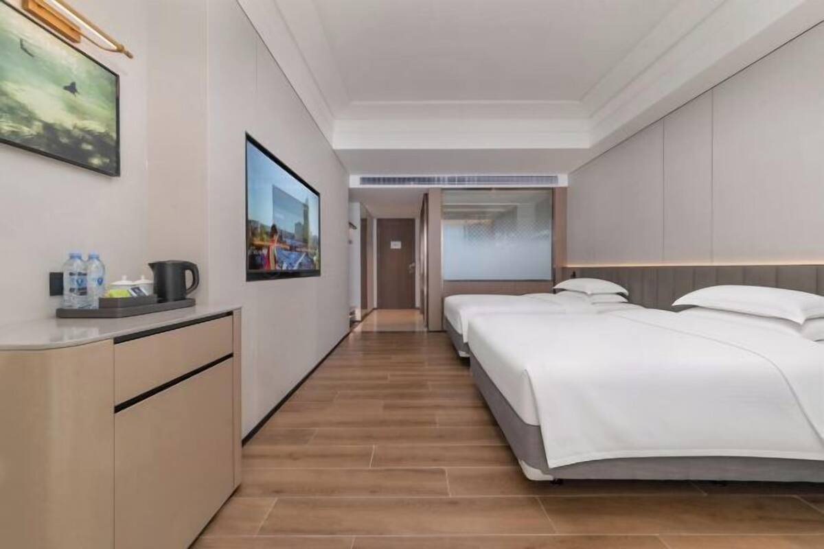 Une chambre d’hôtel équipée d’un lit, d’un bureau, d’une chaise, d’une télévision et d’une porte donnant sur une autre pièce.