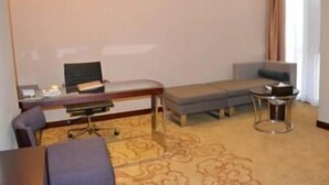 Habitación de hotel con escritorio, silla, sofá y una pequeña mesa redonda.