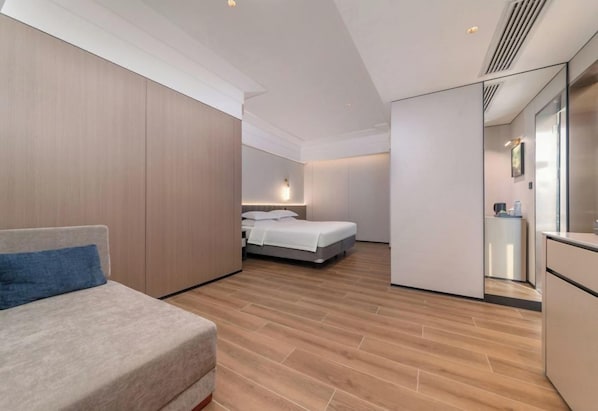 Una habitación de hotel moderna con cama, sofá y una zona de kitchenette.