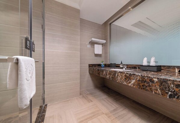 Un baño moderno con cabina de ducha de vidrio, encimera de mármol y un espejo grande.