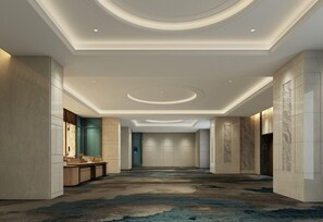 A hotel corridor with a modern design, featuring a central light fixture and a carpeted floor.