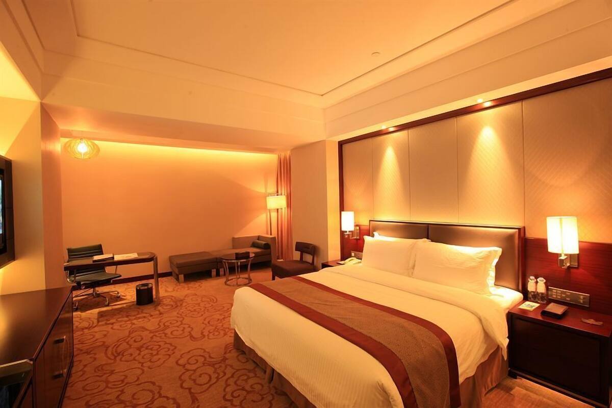 Une chambre d’hôtel avec un grand lit, des tables de chevet, un bureau, une chaise et un téléviseur.