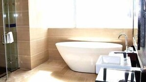 Un baño moderno con una bañera independiente, cabina de ducha de vidrio y tocador con espejo.