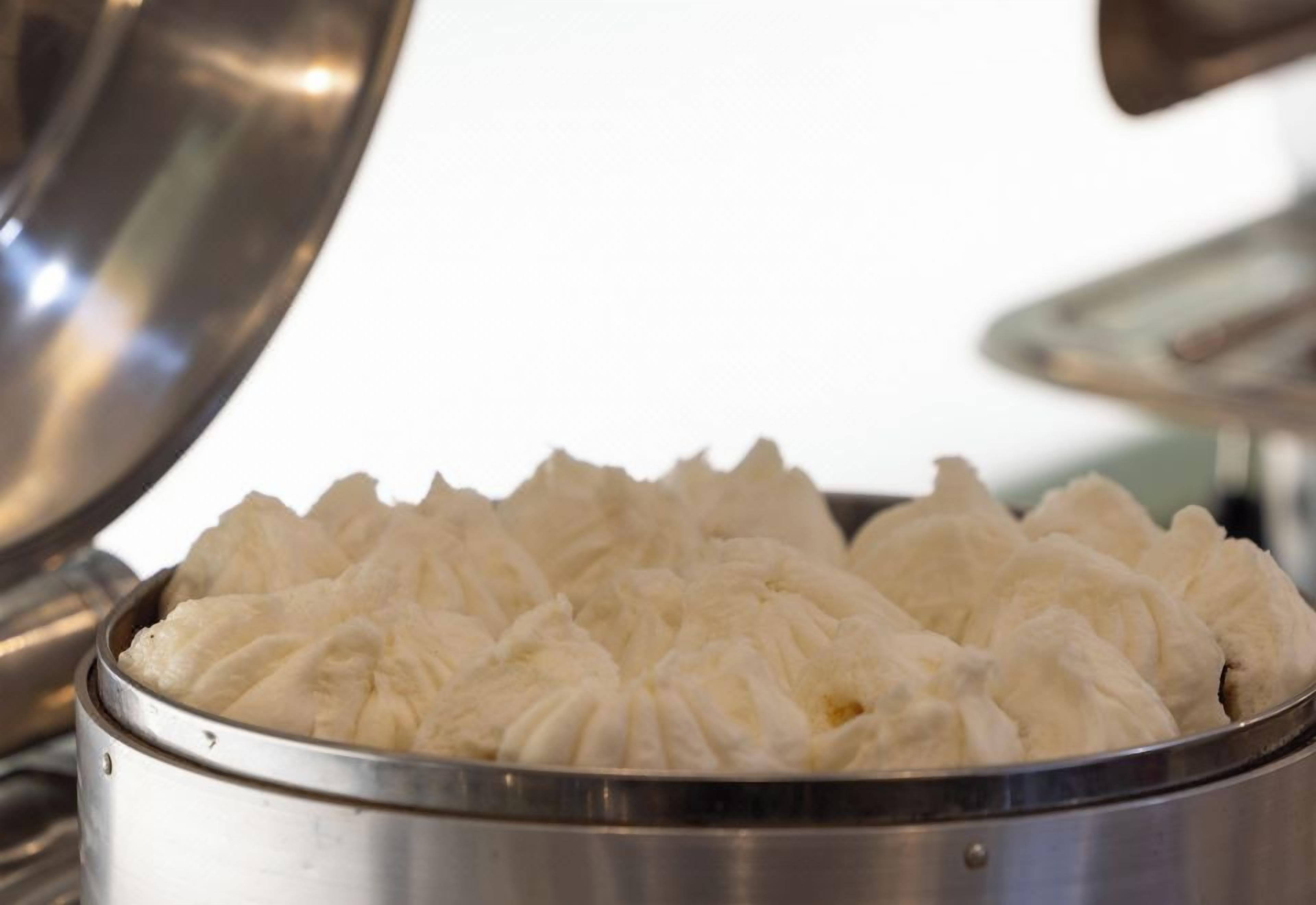 Un recipiente de acero inoxidable con tapa, que contiene un alimento blanco y esponjoso.