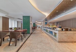 Un moderno hall de hotel con un mostrador de recepción alargado, un área de estar y vistas hacia el comedor.