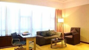 Habitación de hotel con sofá, una silla, una mesita y una lámpara.