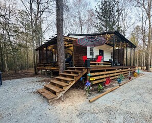 Une cabane en bois dotée d’une terrasse couverte, d’un espace salon extérieur et d’un petit jardin.