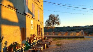 A building with a gravel courtyard, wooden benches, and potted plants. - PetFriendly Holiday Home Among the Vineyards (Bosnasco)