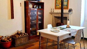 A dining area with a table, chairs, a television, a fireplace, and a cabinet. - PetFriendly Holiday Home Among the Vineyards (Bosnasco)