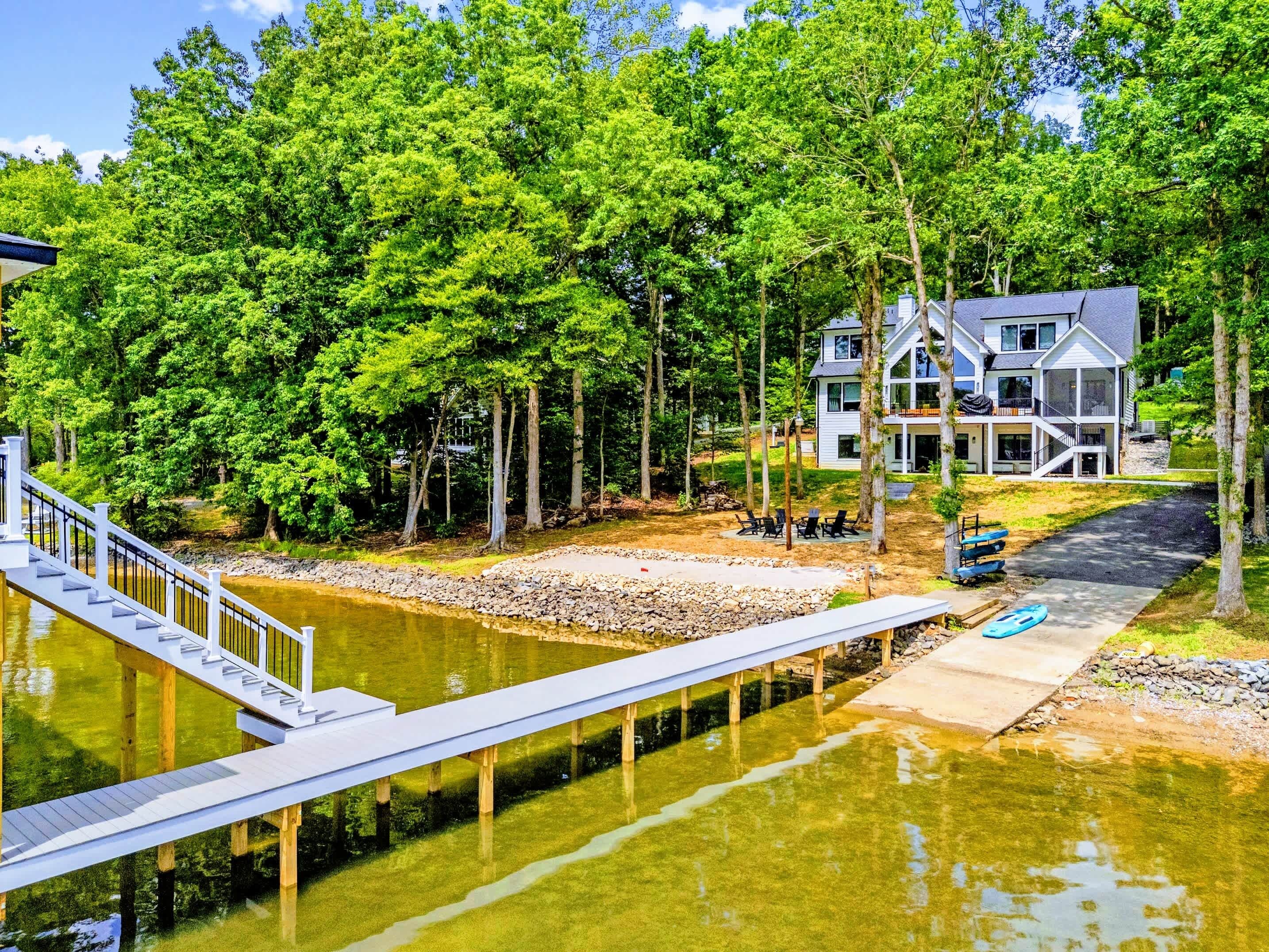 Une propriété au bord du lac, dotée d’un quai, d’une maison à plusieurs niveaux et entourée d’une forêt.