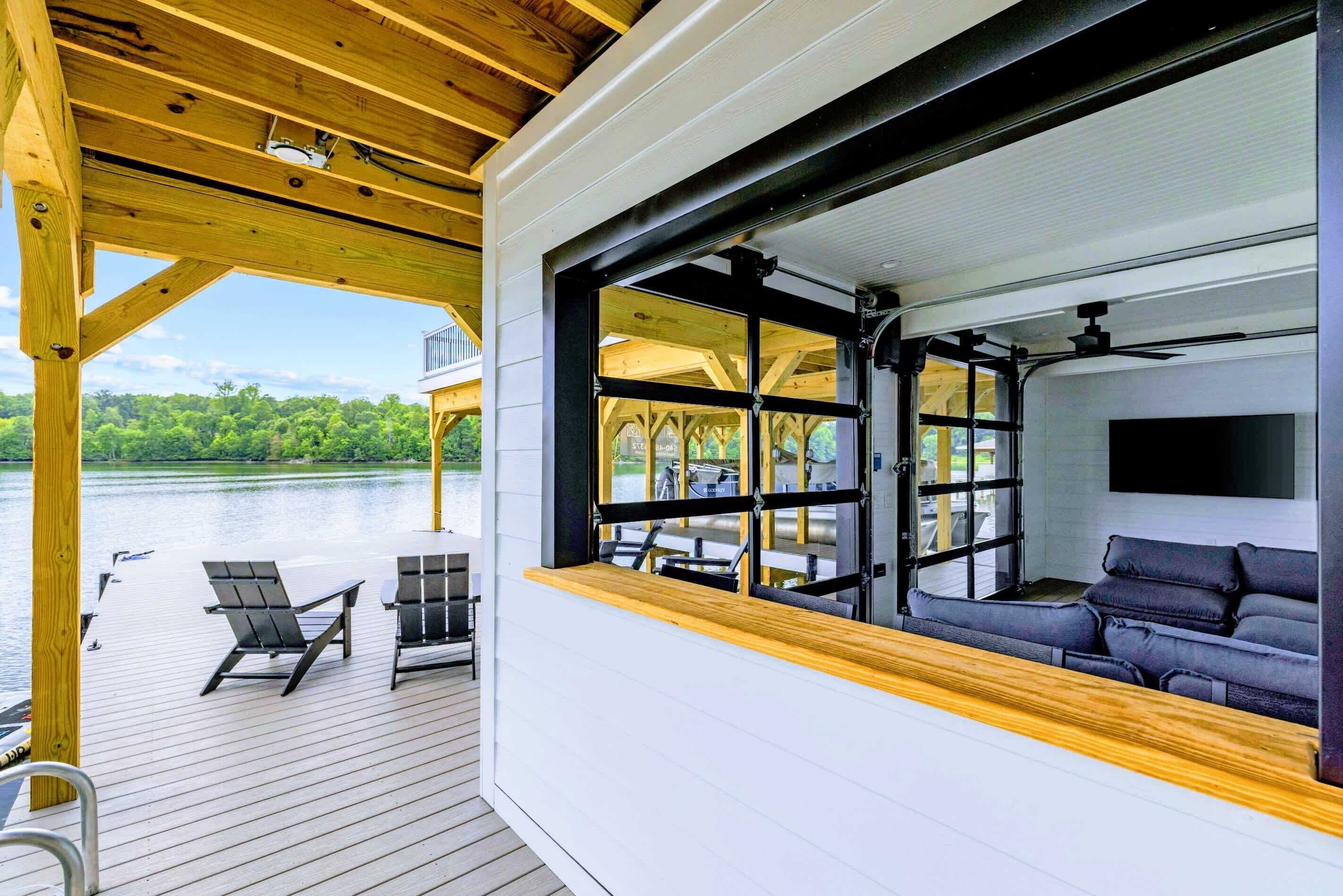 Eine überdachte Terrasse mit Seeblick, eine Sitzecke mit Sofa und Sesseln sowie ein großes Fenster.