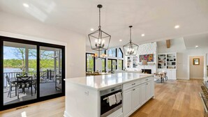 A modern kitchen with a large island, pendant lighting, and a view to an outdoor deck. - Lakefront Lake Anna 5 Suites, Dock, Hot Tub (Spotsylvania Courthouse)