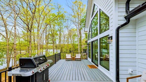 A deck with a grill, two chairs, and a glass-enclosed dining area. - Lakefront Lake Anna 5 Suites, Dock, Hot Tub (Spotsylvania Courthouse)
