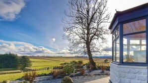 A stone building with a large window overlooking a rural landscape with fields and a tree. - 5 bedroom accommodation in Inverurie (Inverurie)