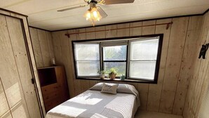 A bedroom with a bed, a ceiling fan, and a window with blinds. - Escape to Comfort Near Higgins Lake! (Roscommon)