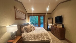 A bedroom with a bed, dresser, TV, and a window with a view of greenery. - Luxury Lodge Retreat in the Heart of Suncadia – Walk to Golf, Winery & Trails (Cle Elum)