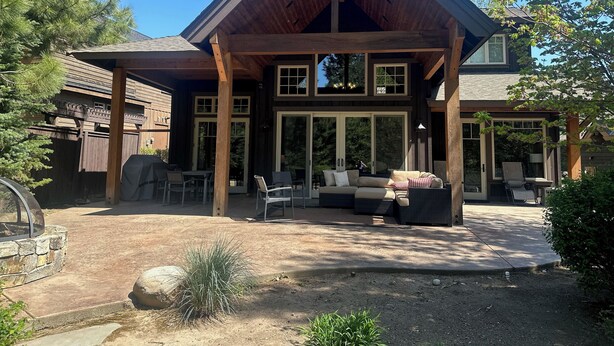 A wooden house with a covered patio, outdoor seating, and a stone fire pit. - Luxury Lodge Retreat in the Heart of Suncadia – Walk to Golf, Winery & Trails (Cle Elum)