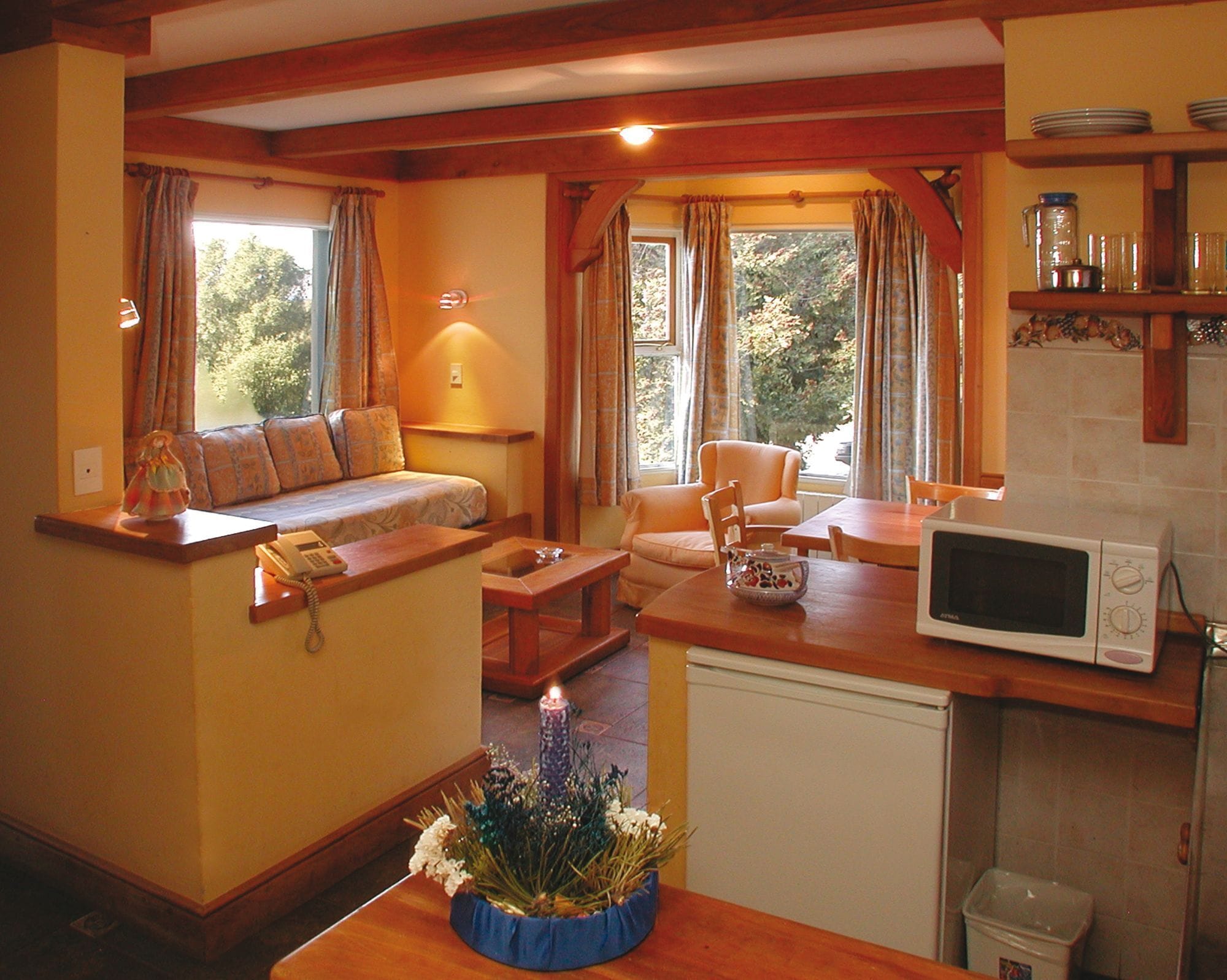 Una sala de estar acogedora con un sofá, una mesa de comedor y una zona de cocina con microondas.