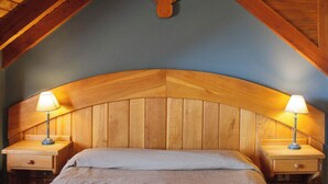 A bedroom with a wooden ceiling, a curved headboard, and two bedside tables with lamps. - Rupu Pehuen Resort (San Carlos de Bariloche)