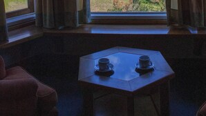 Una habitación con vista a un bosque y una mesa con dos tazas.