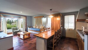 A cozy room with a wooden dining table, chairs, a sofa, and a kitchen area with a refrigerator and cabinets. - Rupu Pehuen Resort (San Carlos de Bariloche)