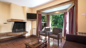 Una sala de estar con chimenea, televisión y dos sillones.