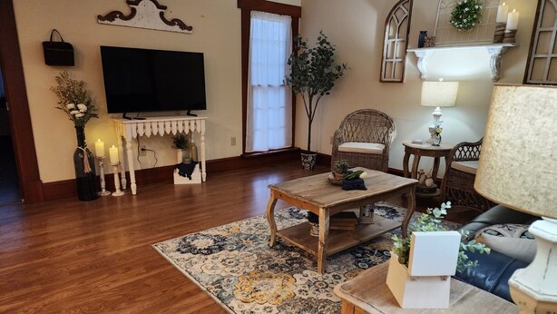 A living room with a wooden floor, a television, a fireplace, a dining table, and a sofa.