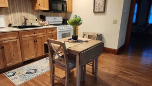 A kitchen with wooden cabinets, a microwave, a stove, a sink, and a dining table with chairs.