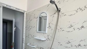 A bathroom with a marble wall, a sink, a mirror, and a shower. - DORTOIR ADAM (Algiers)