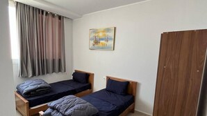 A room with two wooden beds, a painting on the wall, a window with curtains, and a wardrobe. - DORTOIR ADAM (Algiers)