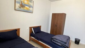 A bedroom with two single beds, a wooden wardrobe, a painting on the wall, and a ceiling light. - DORTOIR ADAM (Algiers)