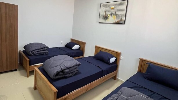 A room with three wooden beds, a wooden wardrobe, and a ceiling light. - DORTOIR ADAM (Algiers)