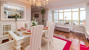 Un comedor con candelabro, mobiliario blanco y un ventanal con vistas.