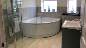 A modern bathroom with a large freestanding bathtub, a separate sink, and a glass shower enclosure. - Pen Y Frith Bungalow (Prestatyn)