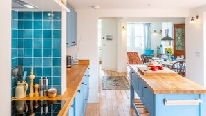 A modern kitchen with blue cabinets, a wooden countertop, and a dining area with a table and chairs. - Ocean View, Walberswick (Walberswick)