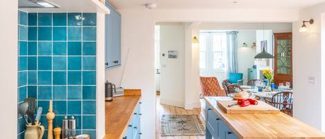 Une cuisine moderne avec des meubles bleus, un plan de travail en bois et un coin repas comprenant une table et des chaises.