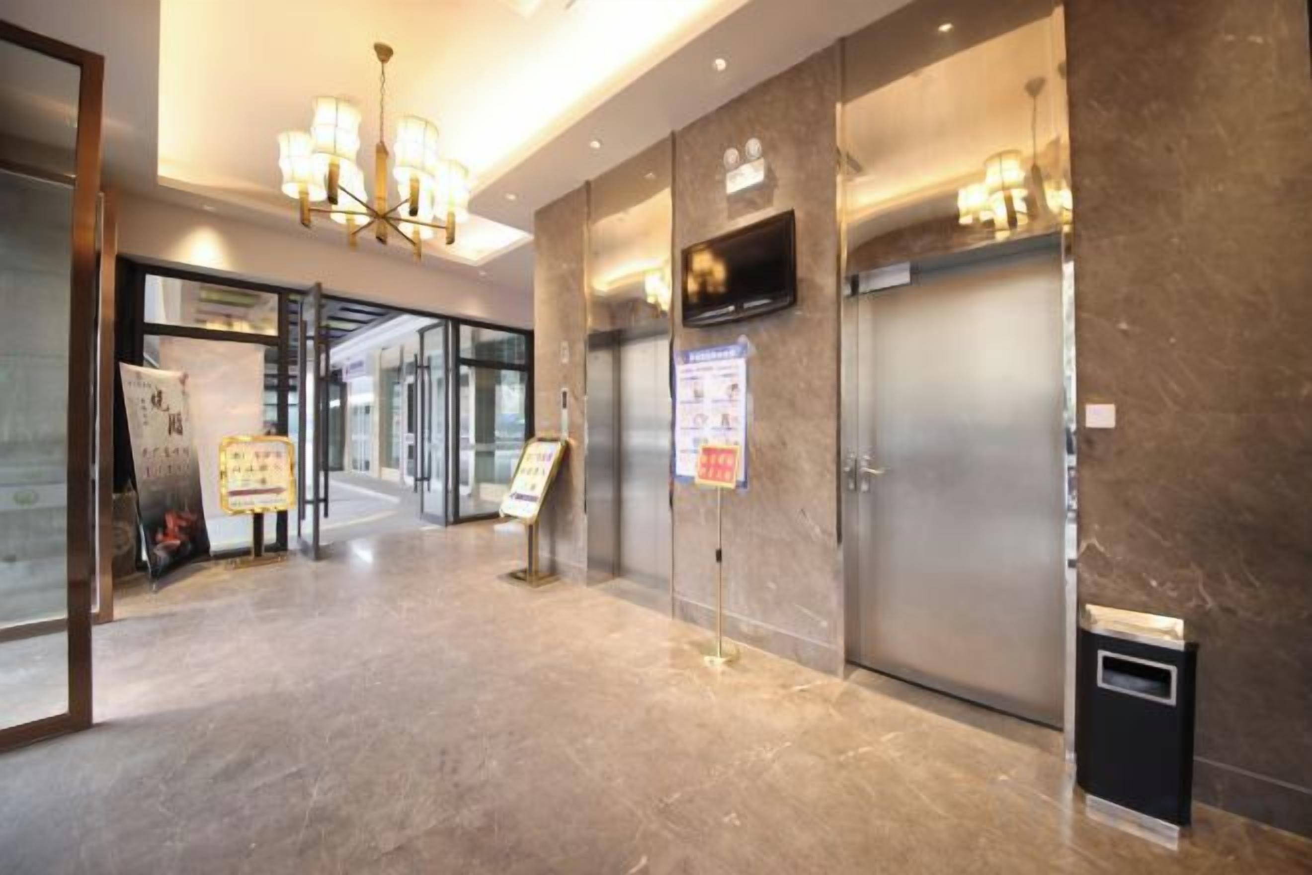 A hotel lobby with a reception desk, a glass door entrance, and a trash bin.