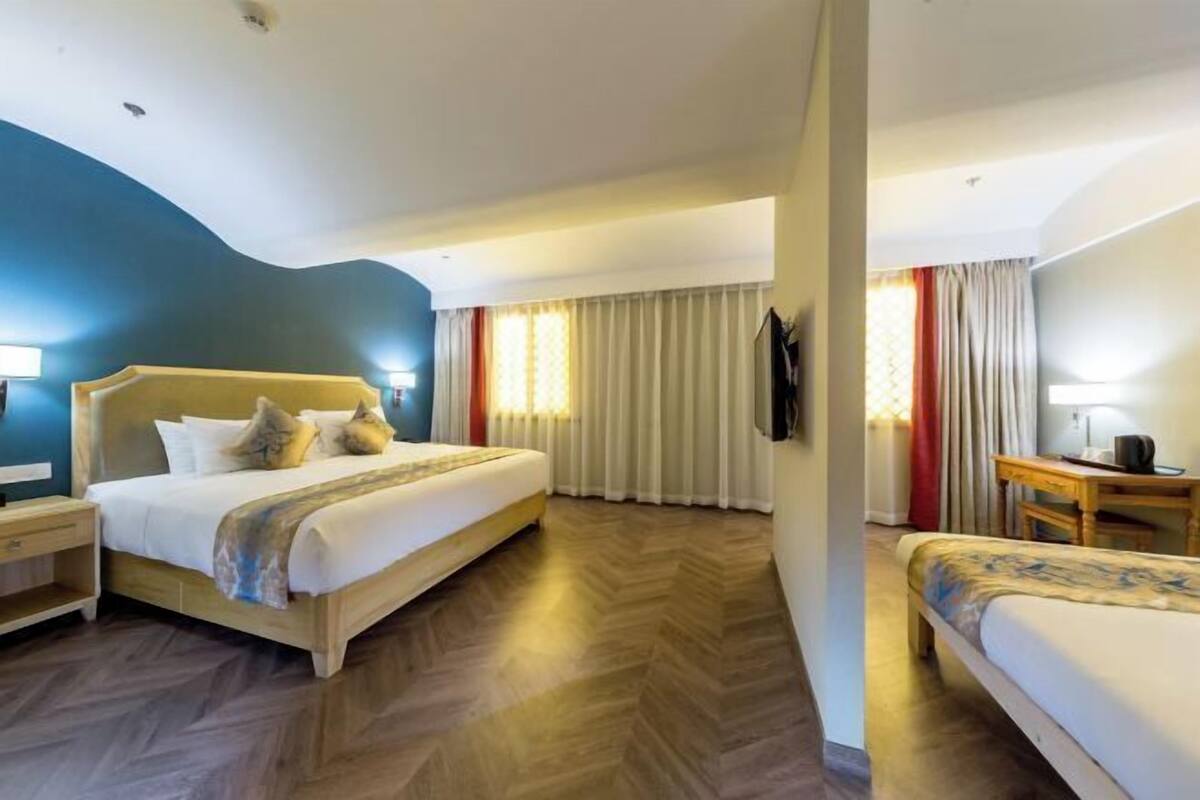 A hotel room with a bed, bedside table, and a desk with a chair.